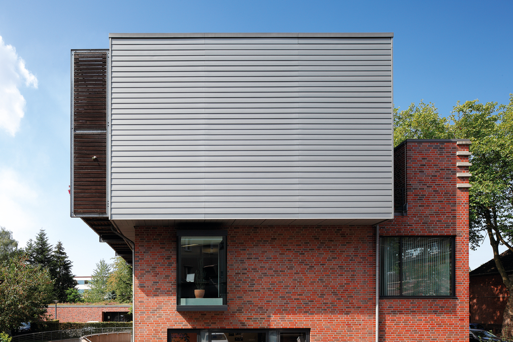 Maison individuelle avec façade en profilés à clins zinc combinés à de la brique